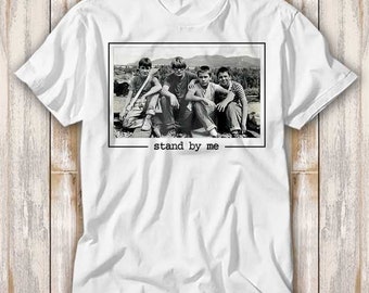 May include: White t-shirt with a black and white photo of four boys standing on a railroad track. The photo is framed with a black border and the text "stand by me" is printed below the photo.