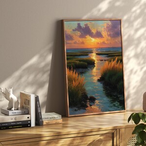 a wooden shelf with a framed painting of a sunset landscape, a stack of books, and a small white ceramic figurine.