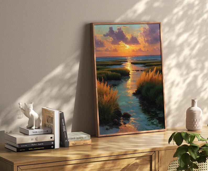 a wooden shelf with a framed painting of a sunset landscape, a stack of books, and a small white ceramic figurine.