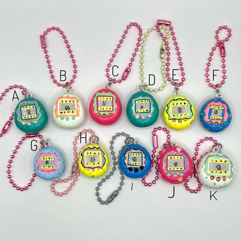 Puede incluir: Una colecci&oacute;n de once llaveros coloridos en forma de huevo. Cada llavero presenta un dise&ntilde;o pintado con una peque&ntilde;a pantalla y caracteres japoneses. Los llaveros est&aacute;n sujetos a cadenas de bolas rosas o plateadas. Los colores incluyen turquesa, blanco, rosa, verde, amarillo, azul y azul claro.