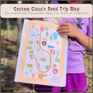 May include: A custom road trip map with a personalized design for kids and families. The map features a route with illustrations of landmarks, including Yellowstone National Park, and the text "Custom Classic Road Trip Map". The map is held by a person wearing a purple shirt.