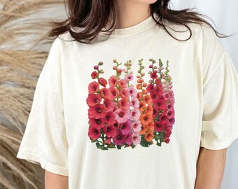 May include: A white t-shirt with a graphic print of a cluster of pink, red, and orange flowers. The flowers are arranged in a vertical line and have a delicate, feminine look.