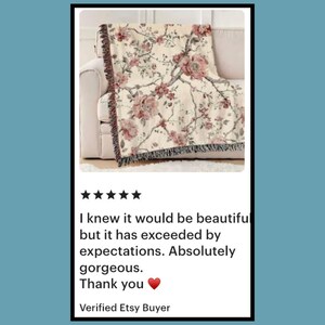 May include: A beige floral throw blanket with a botanical design featuring pink flowers and green leaves. The blanket is draped over a white sofa. The image includes customer feedback: "I knew it would be beautiful...Absolutely gorgeous."