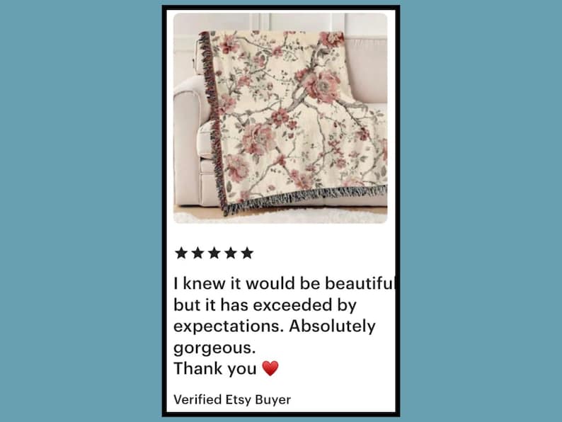 May include: A beige floral throw blanket with a botanical design featuring pink flowers and green leaves. The blanket is draped over a white sofa. The image includes customer feedback: "I knew it would be beautiful...Absolutely gorgeous."