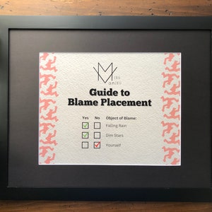 May include: A framed print with a black frame and a white background. The print has a pink and white pattern on the sides and the text "Guide to Blame Placement" in black. The print has a checklist with the text "Falling Rain", "Dim Stars", and "Yourself" with checkboxes next to each.