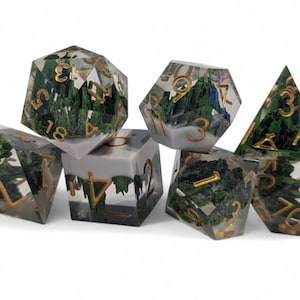 May include: Set of seven clear resin dice with gold numbers and green foliage embedded inside. The dice are in various shapes, including a d20, d12, d10, d8, d6, d4, and a d%.