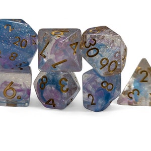 Puede incluir: Conjunto de siete dados iridiscentes con remolinos azules y morados y números dorados. Los dados son un d4, d6, d8, d10, d%, d12 y d20.