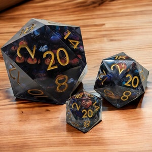 May include: Three clear, multi-sided dice with gold numbers and a galaxy-themed design. The dice are made of resin and have a translucent appearance.