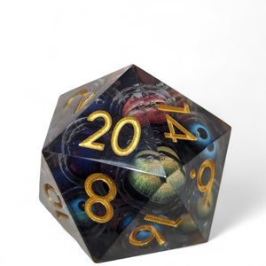 May include: A clear, multi-sided dice with gold numbers and a black and blue eye pattern. The dice is a 20-sided die.