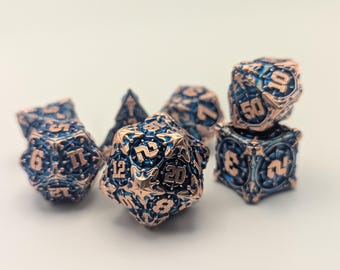 May include: A set of polyhedral dice in blue and copper. The dice are intricately designed with detailed edges and numbers. The dice are used for tabletop role-playing games.