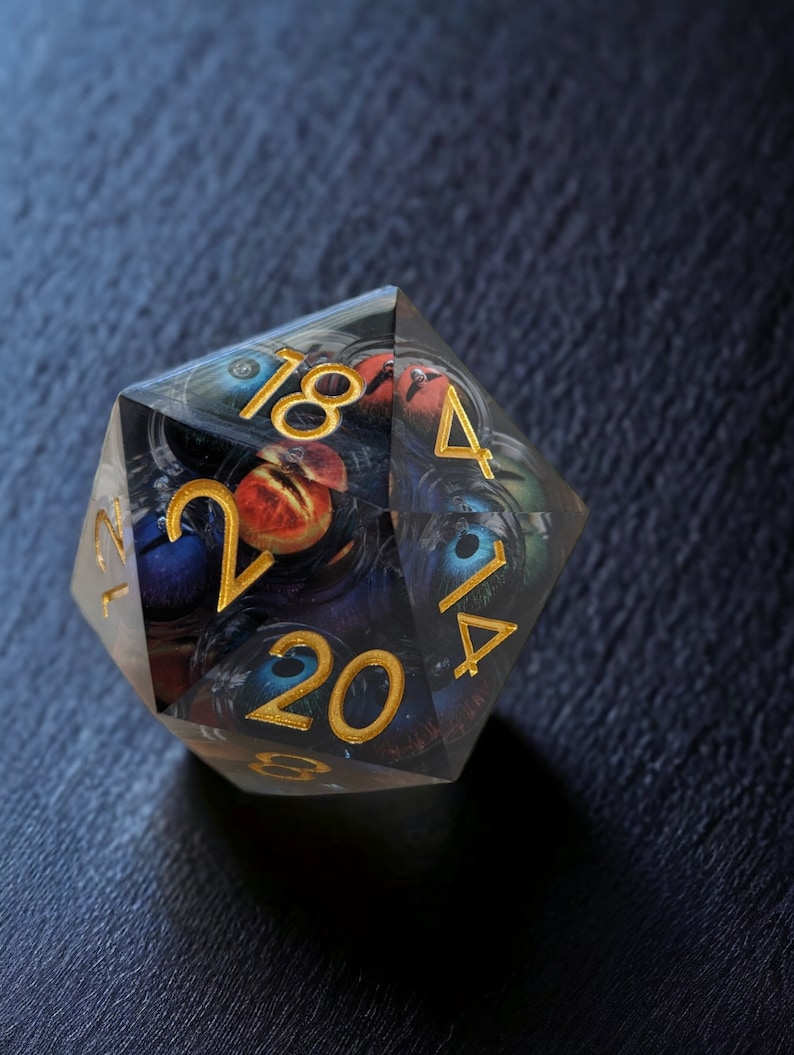 May include: A clear, multi-sided dice with gold numbers 1, 2, 4, 14, 18, 20, and a swirling, abstract design.