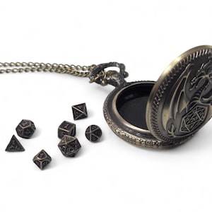 May include: A bronze dragon-shaped pocket watch pendant with a chain and a set of metal dice. The watch is open and the inside is black.