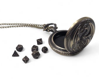May include: A bronze dragon-shaped pocket watch pendant with a chain and a set of metal dice. The watch is open and the inside is black.