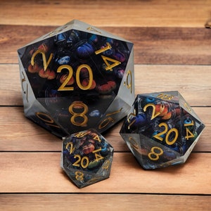 May include: Three clear, multi-sided dice with black and gold numbers and a colorful, abstract design inside. The dice are on a wooden surface.