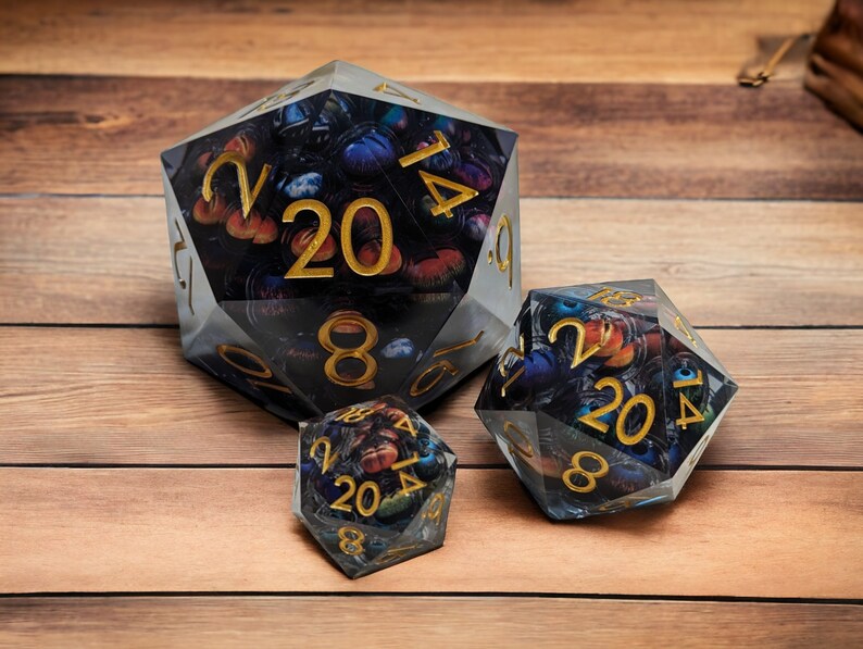 May include: Three clear, multi-sided dice with black and gold numbers and a colorful, abstract design inside. The dice are on a wooden surface.