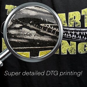 May include: Close-up of a black t-shirt with yellow text that reads "The Art of Being" and a magnified image of the print showing the detail of the design. The text "Super detailed DTG printing!" is below the image.