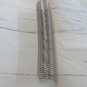 May include: A silver metal coil spring, a common type of spring used in various applications.