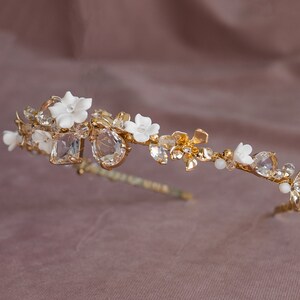 May include: A gold bridal headband with white porcelain flowers and clear crystal accents.