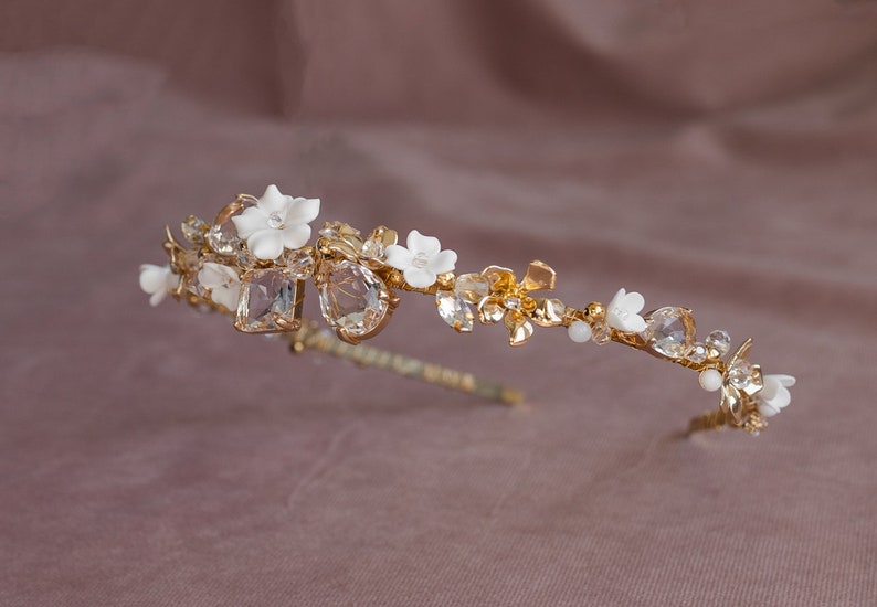 May include: A gold bridal headband with white porcelain flowers and clear crystal accents.