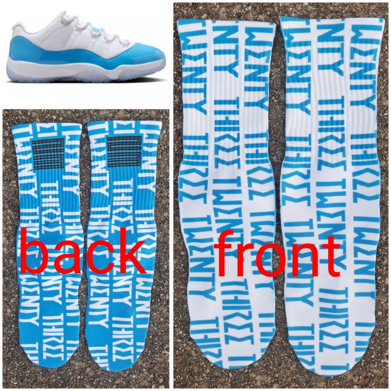 May include: White and light blue athletic shoes and two pairs of white socks. The socks feature the words "TWENTY THREE" in light blue repeated vertically. The back of the socks have a light blue and black design.