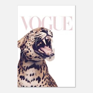 Può includere: Una stampa raffigurante un leopardo ruggente con la bocca spalancata, che mostra denti affilati e una lingua rosa. La parola "VOGUE" è visualizzata in un carattere rosa tenue sopra la testa del leopardo, su sfondo bianco.