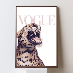 Puede incluir: Impresión enmarcada de un leopardo rugiendo con la boca abierta y los dientes visibles. La palabra "VOGUE" está impresa en rosa encima del leopardo. El leopardo tiene un pelaje manchado marrón y negro.