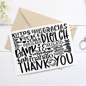 May include: A white card with a black word cloud of thank you in different languages, including "Thank You", "Merci", "Gracias", "Danke", "Grazie", "Obrigado", "Arigato", "Diolch", "Mahalo", "Tak", "Kitos", "Dankie", "Dziekuje", and "Takk".