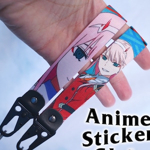 May include: Two anime character lanyards with black metal clips. The lanyards feature a pink and blue background with a female anime character with pink hair and blue eyes. The text "Anime Sticker Club" is visible in the bottom right corner of the image.