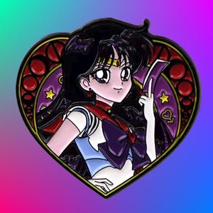 May include: A heart-shaped enamel pin featuring a cartoon anime character with black hair, a red and blue sailor uniform, and a purple bow. The character is holding a card with a star and a heart symbol. The pin has a stained glass design with red, purple, and yellow accents.