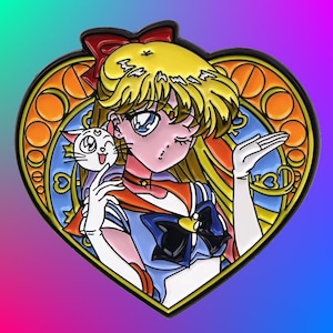 May include: A heart-shaped enamel pin featuring a cartoon character with blonde hair, a blue and red sailor uniform, and a white cat. The character is winking and holding the cat in her right hand. The background is a stained glass design with a yellow, orange, and blue color scheme.