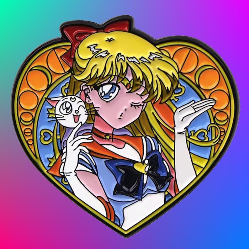 May include: A heart-shaped enamel pin featuring a cartoon character with blonde hair, a blue and red sailor uniform, and a white cat. The character is winking and holding the cat in her right hand. The background is a stained glass design with a yellow, orange, and blue color scheme.