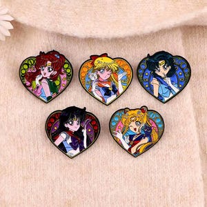 May include: Five enamel pins featuring characters from the anime Sailor Moon. Each pin is shaped like a heart and features a different Sailor Scout in a colorful, detailed design.