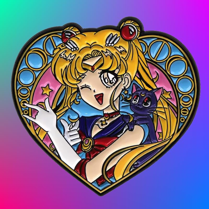 May include: A heart-shaped enamel pin featuring a cartoon anime character with blonde hair, a blue and red outfit, and a black cat. The character is holding a hand up in a peace sign. The pin has a stained glass design with blue, pink, and yellow colors.