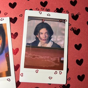 May include: A Polaroid photo of a young person with dark hair looking at the camera. The photo is surrounded by red hearts.