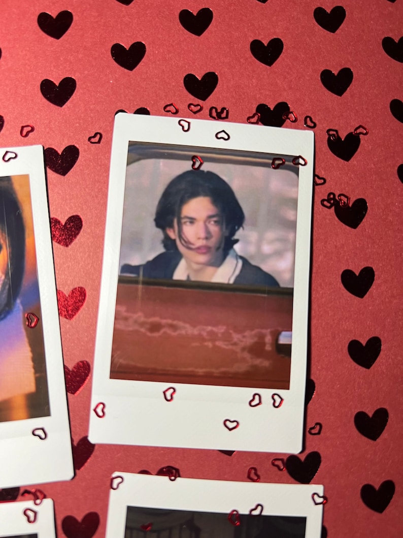 May include: A Polaroid photo of a young person with dark hair looking at the camera. The photo is surrounded by red hearts.