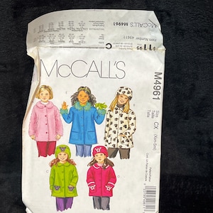 Könnte beinhalten: Ein McCall's M4961 Schnittmusterumschlag für Kinder-Fleecejacken. Die Vorderseite zeigt Illustrationen von fünf Kindern, die verschiedene Arten von Fleecejacken in Pink, Blau, Weiß mit schwarzen Pfotenabdrücken, Limettengrün und Rot tragen.