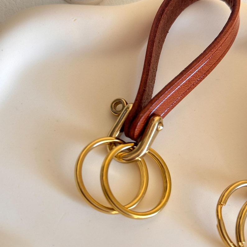 May include: A brown leather keychain with a gold metal loop and two gold metal key rings.