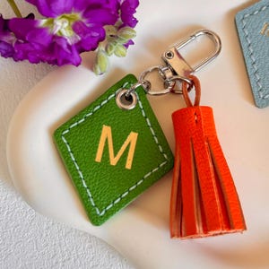 May include: Green leather keychain with a gold letter M and an orange tassel.