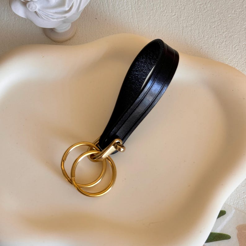 May include: A black leather keychain with a gold double ring.