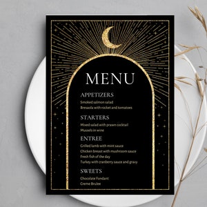 May include: A black and gold menu card with a crescent moon and stars design. The menu includes appetizers, starters, entree, and sweets. The text reads: "MENU", "APPETIZERS", "Smoked salmon salad", "Bresaola with rocket and tomatoes", "STARTERS", "Mixed salad with prawn cocktail", "Mussels in wine", "ENTREE", "Grilled lamb with mint sauce", "Chicken breast with mushroom sauce", "Fresh fish of the day", "Turkey with cranberry sauce and gravy", "SWEETS", "Chocolate Fondant", "Creme Brulee".