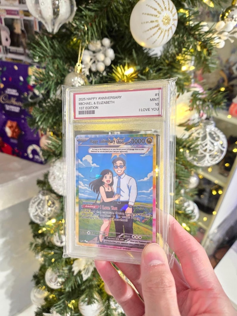 May include: A custom trading card in a clear protective slab featuring an anime-style illustration of a couple. The label reads 2025 HAPPY ANNIVERSARY MICHAEL & ELIZABETH 1ST EDITION MINT 10 I LOVE YOU. The card displays a couple standing in a field.