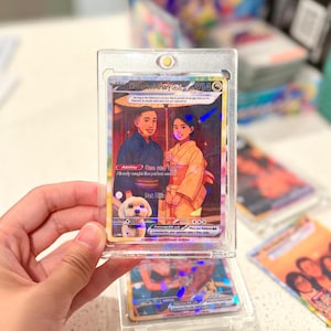 May include: A custom trading card in a clear magnetic protective case featuring an illustration of two people in traditional Japanese clothing holding an umbrella with a small white dog. The card text includes Happy Anniversary ex, Ability One and Only, and Pet Ellie.