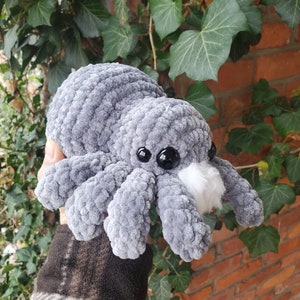 May include: A grey crocheted spider plush toy with black eyes and a white fuzzy patch on its head.
