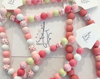 beautiful pink and white wooden beaded necklaces for toddlers. wooden gifts for toddlers. pink beaded necklaces for children’s on eleastic.