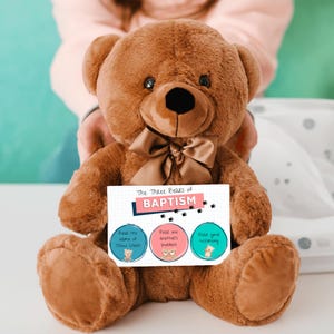 May include: A brown teddy bear holding a card with the text "The Three Bears of Baptism". The card has three circles with bears on them. The first circle says "Bear the name of Jesus Christ", the second circle says "Bear one another's burdens", and the third circle says "Bear your testimony".