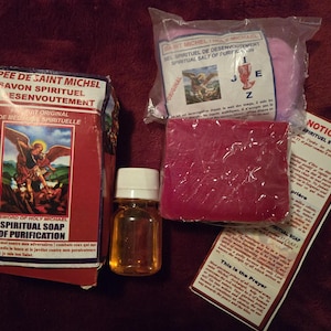 Peut inclure: Ensemble de produits spirituels, comprenant une boîte de savon rouge avec le texte "Sword of Holy Michael Spiritual Soap of Purification", une bouteille d'huile, un paquet de sel rose et un pain de savon rouge.