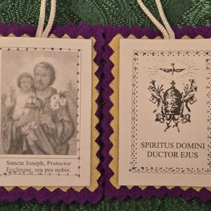 May include: Two religious prayer cards with a purple and yellow felt border and white cord. One card features an image of a man and child with the text "Sancte Joseph, Protector Ecclesiae, ora pro nobis." The other card has an emblem and the text "Spiritus Domini Ductor Ejus."