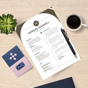 May include: A resume and cover letter with the name "Morgan Maxwell" and the title "Graphic Designer" are displayed on a wooden surface. A pen, a cup of coffee, a succulent plant, and a business card are also present.