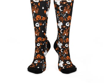 Puede incluir: Un par de calcetines negros con temática de Halloween. Los calcetines presentan un patrón repetido de calabazas naranjas, fantasmas blancos, casas encantadas marrones, calaveras blancas y esqueletos. Los calcetines son hasta la rodilla y de material suave.