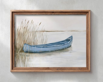 May include: A framed landscape painting depicting a light blue canoe resting on calm water next to tall, thin, tan-colored reeds. The scene features a soft, muted color palette with a light gray sky and water, all enclosed in a wooden frame.